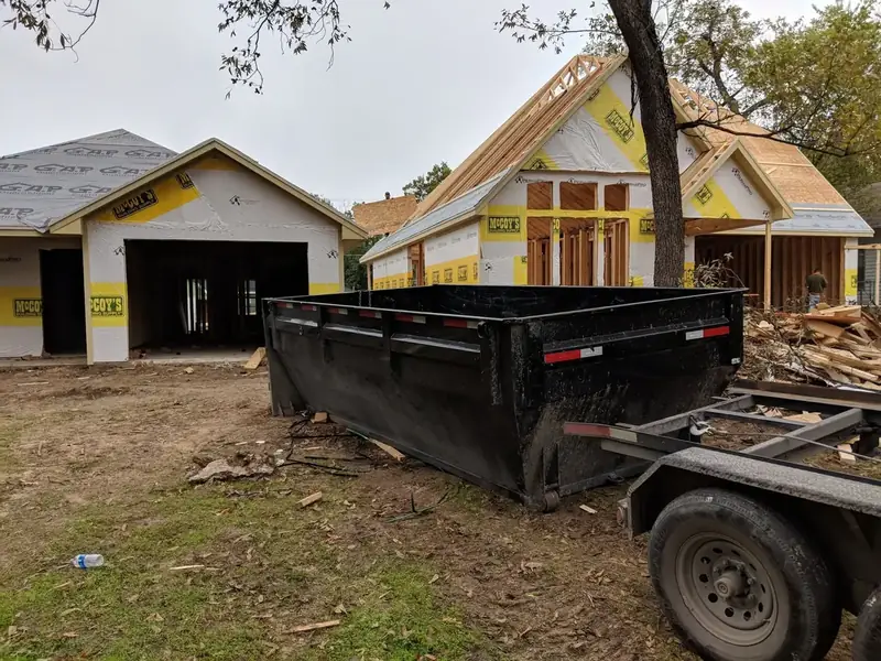 Dumpster trailer beside new homes under construction