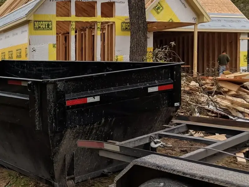 Dumpster next to a pile of broken lumber